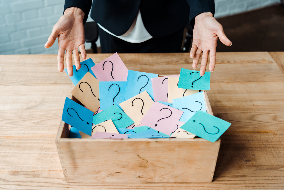 Question marks on sticky notes in a box